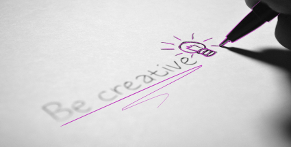 Be creative auf Papier. Dahinter eine Glühbirne, die gerade zuende gezeichnet wird.